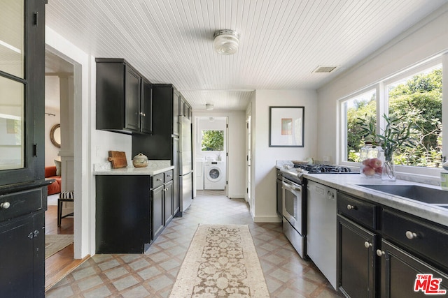 kitchen featuring light floors, washing machine and dryer, dark cabinets, and dishwasher