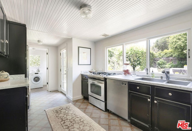 kitchen featuring stainless steel appliances, washer / clothes dryer, a sink, and light floors