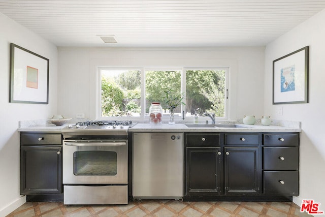 kitchen featuring a healthy amount of sunlight, light floors, stainless steel appliances, and a sink