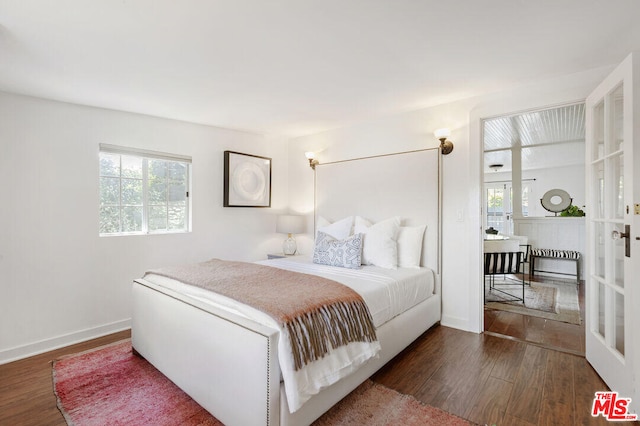 bedroom featuring multiple windows, wood finished floors, and baseboards