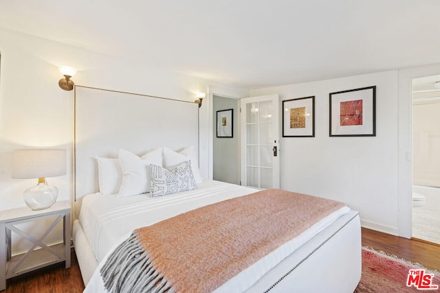 bedroom with ensuite bath and dark wood-style flooring