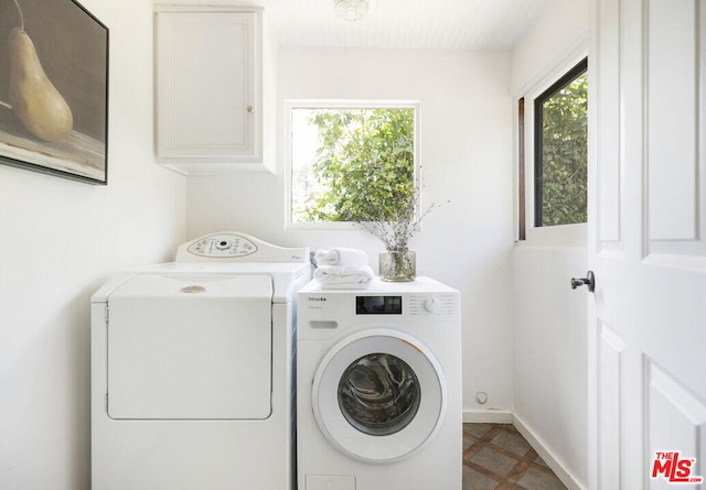 washroom featuring cabinet space, baseboards, a wealth of natural light, and washer and dryer