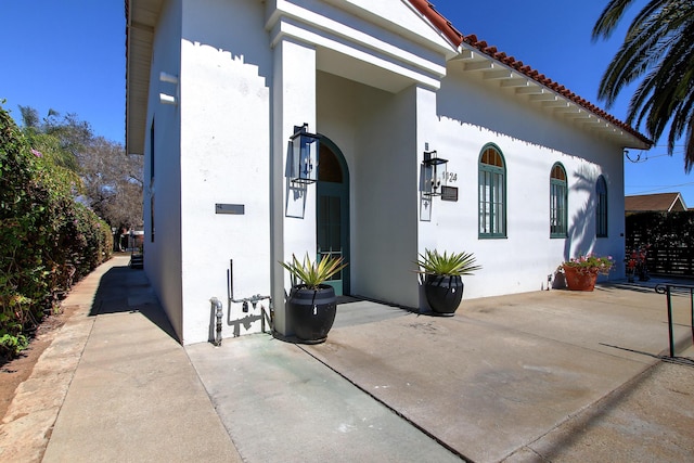 view of property exterior with a patio area, a tile roof, and stucco siding