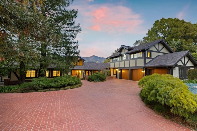 tudor home with a garage, decorative driveway, and stucco siding