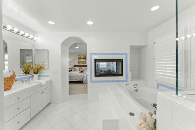 full bath featuring a multi sided fireplace, a garden tub, recessed lighting, ensuite bathroom, and vanity