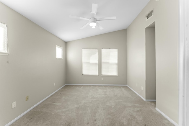 empty room featuring a ceiling fan, baseboards, visible vents, lofted ceiling, and light carpet