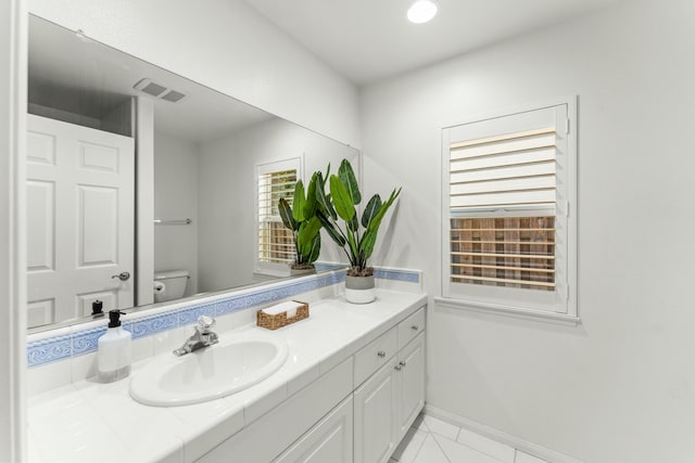 half bath featuring visible vents, baseboards, toilet, and vanity