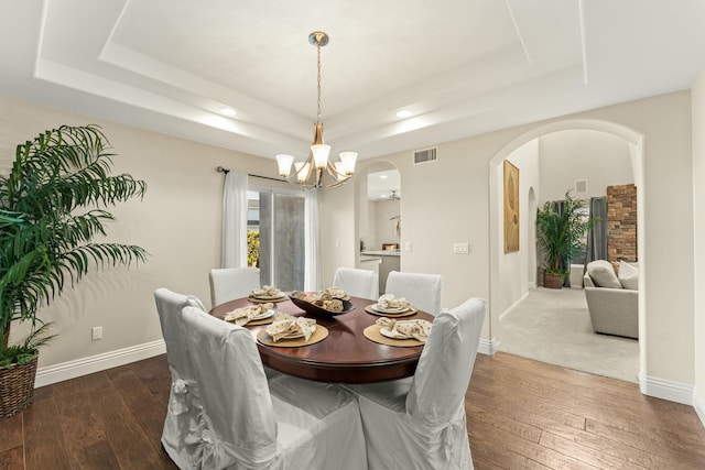 dining space with a tray ceiling, visible vents, and arched walkways