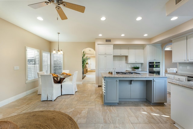 kitchen with white cabinetry, a kitchen island, arched walkways, and stainless steel appliances