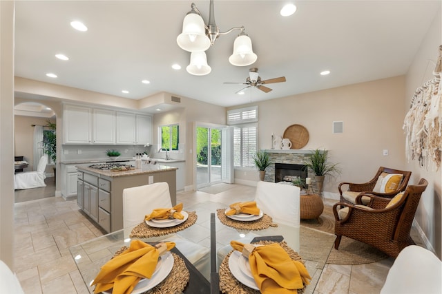 dining area with baseboards, recessed lighting, a fireplace, arched walkways, and ceiling fan