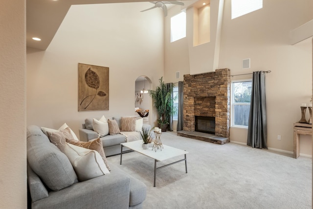 living area with a ceiling fan, visible vents, carpet floors, baseboards, and a stone fireplace