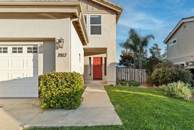 doorway to property with stucco siding, a lawn, fence, board and batten siding, and a garage