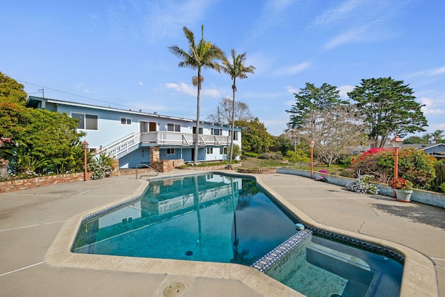 view of swimming pool featuring stairway, a pool with connected hot tub, and a patio