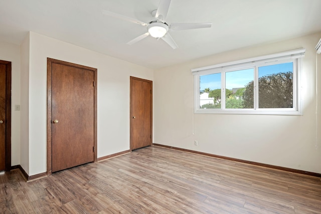 unfurnished bedroom featuring ceiling fan, baseboards, light wood-type flooring, and multiple closets