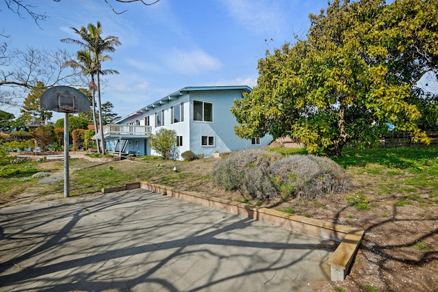 view of home's exterior with stucco siding, a deck, and stairway