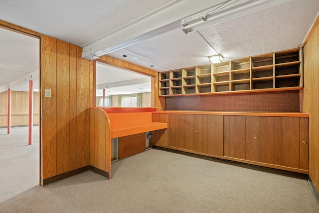 below grade area featuring wooden walls, built in desk, and carpet floors