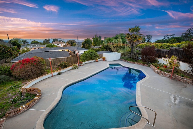 pool at dusk featuring a patio area, a fenced in pool, and a fenced backyard