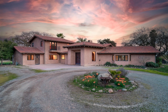 mediterranean / spanish-style home with curved driveway, a chimney, a tile roof, and stucco siding