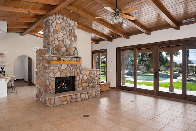 unfurnished living room with arched walkways, a fireplace, visible vents, lofted ceiling with beams, and light tile patterned flooring