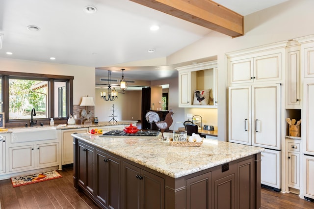 kitchen featuring vaulted ceiling with beams, cream cabinetry, dark wood-type flooring, and a sink