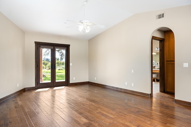 unfurnished room with arched walkways, lofted ceiling, visible vents, wood finished floors, and baseboards