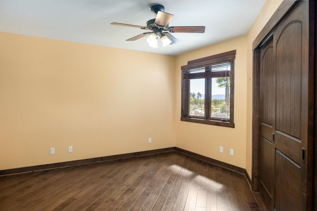 unfurnished bedroom with a ceiling fan, a closet, baseboards, and dark wood-type flooring