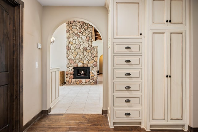 hallway with arched walkways, baseboards, and wood finished floors