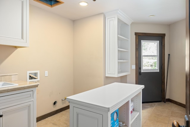 laundry area featuring light tile patterned floors, washer hookup, cabinet space, and baseboards