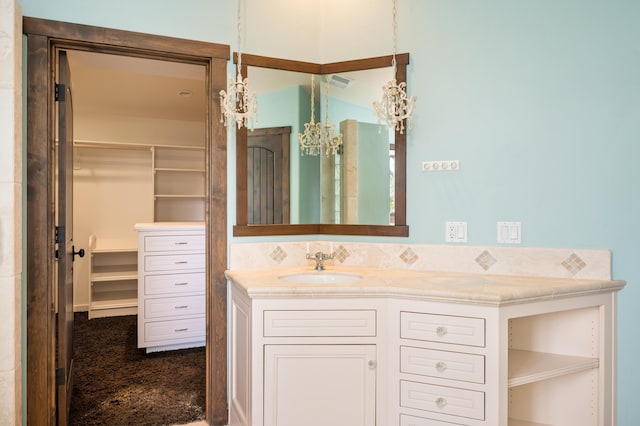 bathroom featuring visible vents, a walk in closet, and vanity