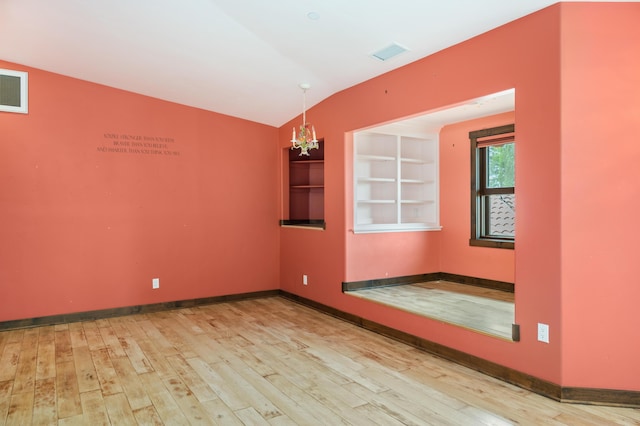 unfurnished room featuring visible vents, vaulted ceiling, baseboards, and wood finished floors