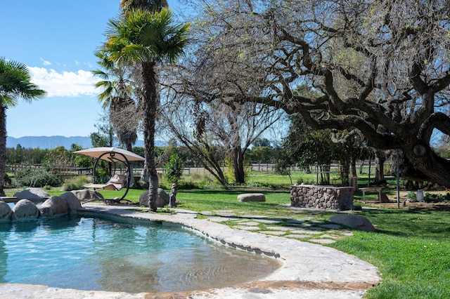 view of property's community featuring a pool, a yard, fence, and a mountain view