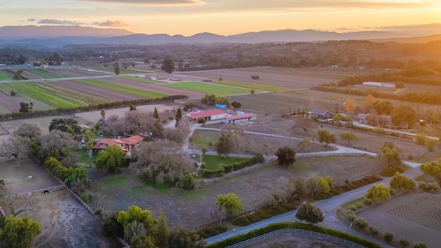 aerial view at dusk featuring a mountain view and a rural view