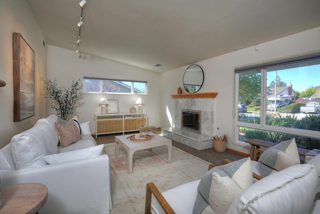 living area featuring a high end fireplace, visible vents, track lighting, vaulted ceiling, and carpet flooring