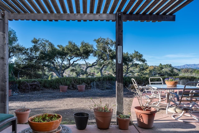 view of patio / terrace with outdoor dining space, a mountain view, and a pergola