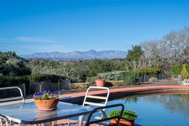 view of swimming pool featuring fence, a mountain view, and a patio