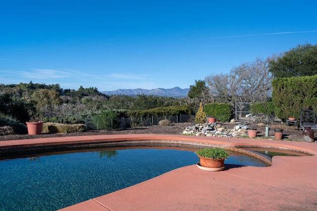 view of swimming pool with fence and a mountain view