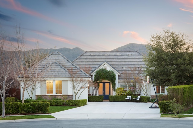 view of front of home featuring a mountain view, stone siding, and stucco siding