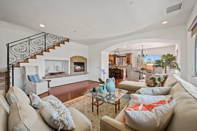 living room featuring visible vents, a glass covered fireplace, wood finished floors, an inviting chandelier, and recessed lighting