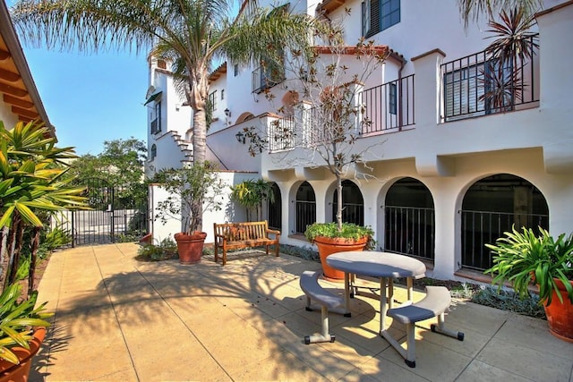 view of patio featuring a balcony and fence