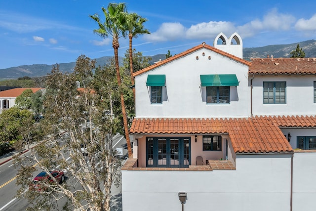 exterior space with a mountain view, a tiled roof, and stucco siding