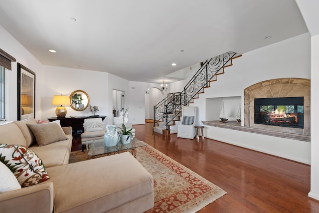 living area with stairway, wood finished floors, an inviting chandelier, a fireplace, and recessed lighting