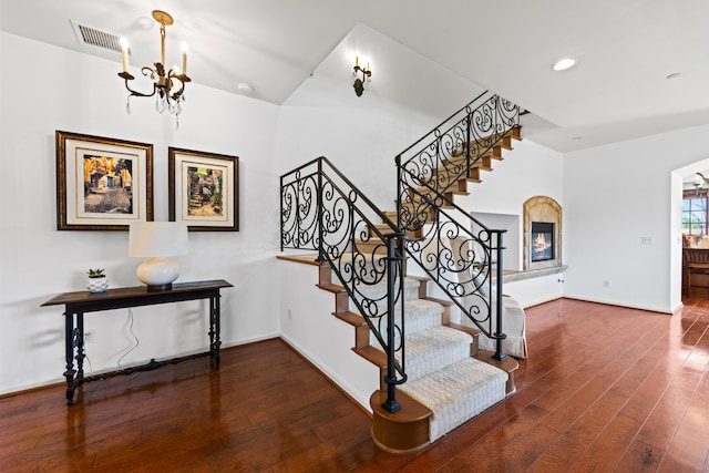 stairway with a chandelier, hardwood / wood-style flooring, visible vents, and baseboards