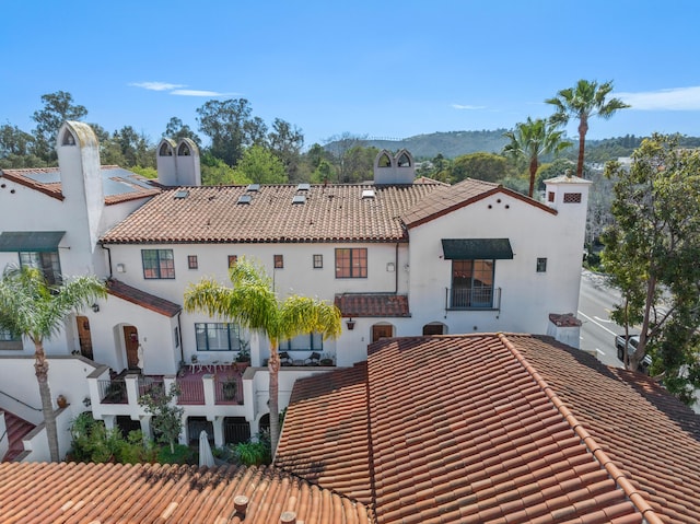 view of front of home with a tiled roof and a chimney