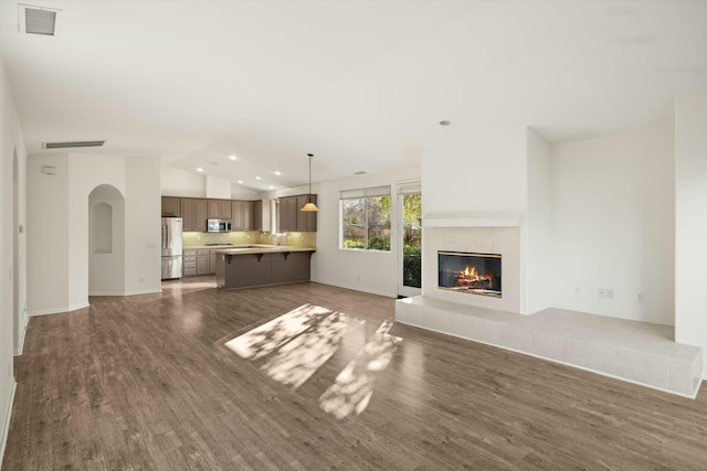 unfurnished living room featuring visible vents, wood finished floors, recessed lighting, a fireplace, and vaulted ceiling