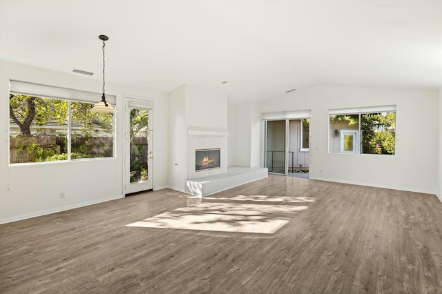 unfurnished living room featuring a fireplace, lofted ceiling, wood finished floors, and visible vents