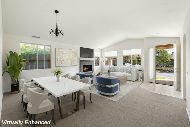 dining space featuring tile patterned floors, a notable chandelier, carpet, a lit fireplace, and vaulted ceiling