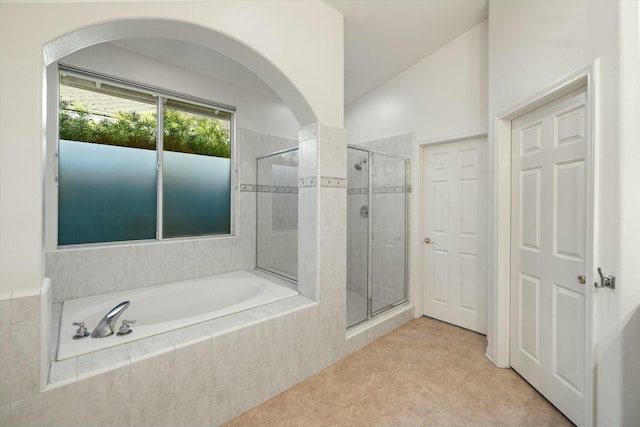 bathroom with a bath, a shower stall, and lofted ceiling