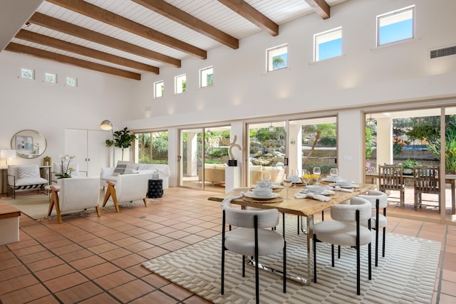 dining room featuring light tile patterned floors, visible vents, beamed ceiling, and a high ceiling