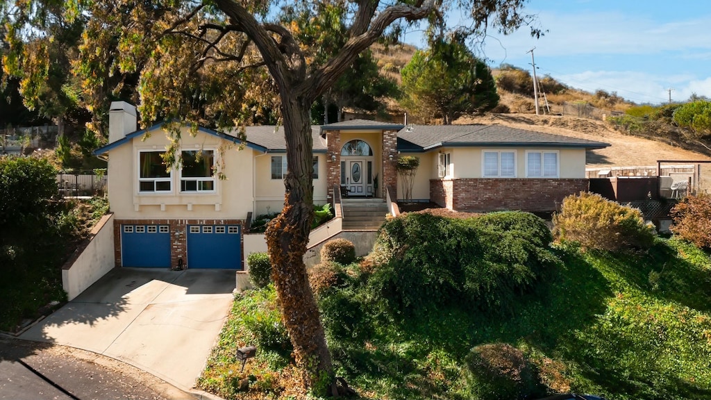 view of front of house with fence, brick siding, driveway, and stucco siding