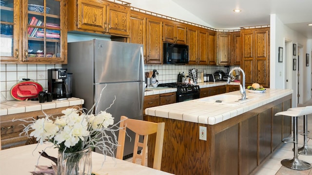 kitchen featuring black appliances, tasteful backsplash, lofted ceiling, and a sink